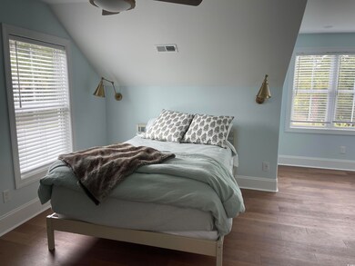 Bedroom featuring lofted ceiling, multiple windows, wood finished floors, and ceiling fan