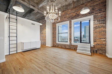 The corner unit features a blend of industrial and modern design with a chandelier, wooden floors, and a metal ladder leading to a loft area for storage
