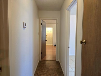 Hallway with a textured ceiling and baseboards