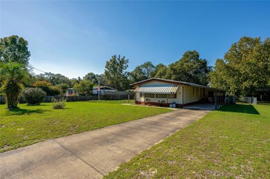 The long driveway leads to a covered carport and additional side entry, offering convenient parking and access.