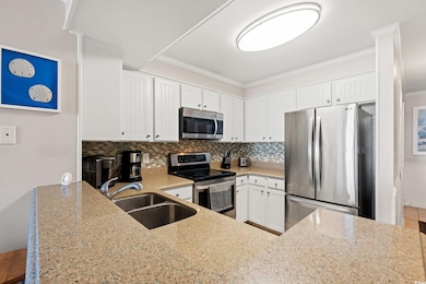 Kitchen with appliances with stainless steel finishes, a sink, light stone countertops, ornamental molding, and tasteful backsplash