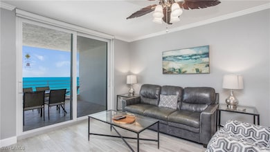 Living area with ornamental molding, wood finish floors, a ceiling fan, and a water view