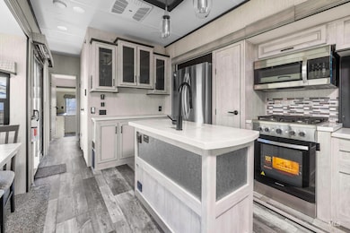 Kitchen with light countertops, appliances with stainless steel finishes, glass insert cabinets, dark wood finished floors, and recessed lighting
