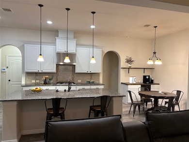 Where Everyone Wants to Gather”

This gorgeous kitchen is the heart of the home—open, bright, and designed for everyday living and memorable entertaining. Crisp white cabinets, granite counters, pendant lighting, and a huge island offer plenty of prep and hangout space. It flows to the breakfast area which means you’re always connected—whether you’re cooking dinner, helping with homework, or hosting weekend brunch. It’s warm, inviting, and truly the soul of the home.