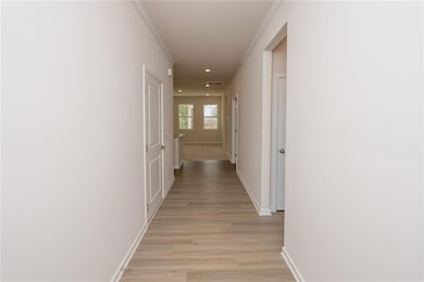 Corridor with baseboards, light wood finished floors, recessed lighting, and ornamental molding