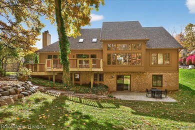 Back of house featuring a lawn, a chimney, brick siding, and a patio