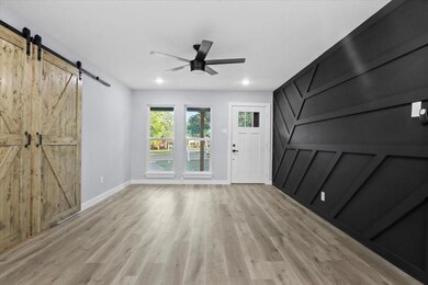 Entryway with ceiling fan, baseboards, a barn door