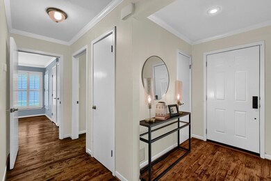 Foyer entrance featuring dark Hand scraped wood-type flooring and crown molding