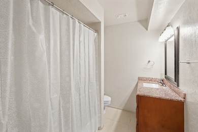 The full bathroom with wood stained cabinets, a spacious tub and shower, and large vanity with granite counters, is located just off the bedroom!