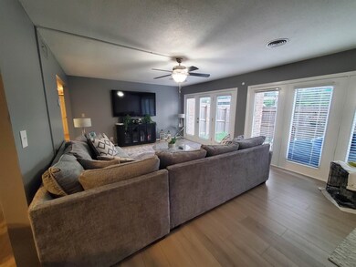Living room featuring a ceiling fan, wood finished floors, and a textured ceiling