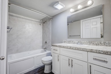 Bathroom featuring washtub / shower combination, vanity, and dark wood-style floors