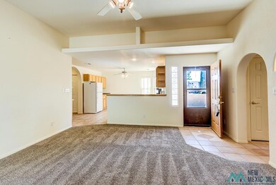 Unfurnished living room with arched walkways, light tile patterned floors, ceiling fan, and light colored carpet