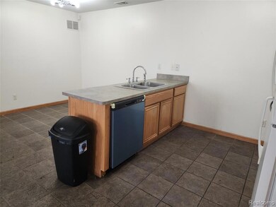 Kitchen featuring a peninsula, dishwasher, freestanding refrigerator, and brown cabinets