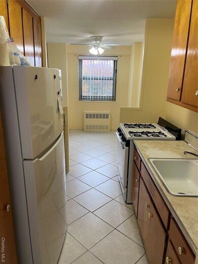 Kitchen featuring brown cabinets, fridge, range, and light tile patterned floors