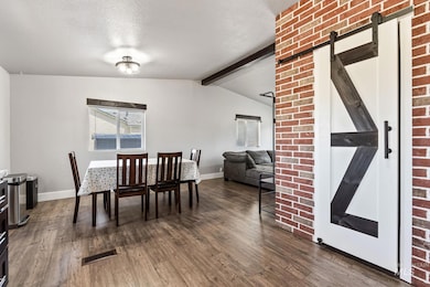 Dining room featuring dark wood-type flooring, a barn door, and a textured ceiling