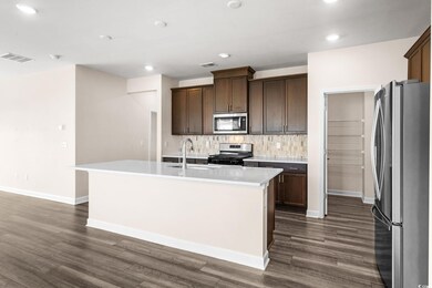 Kitchen with tasteful backsplash, stainless steel appliances, dark brown cabinetry, recessed lighting, and a center island with sink
