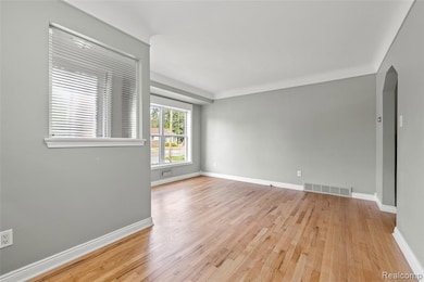 Empty room with arched walkways and light wood finished floors