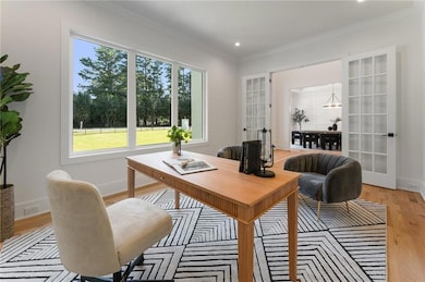 Office with plenty of natural light, light wood-style flooring, crown molding, french doors, and a chandelier