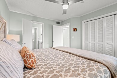 Bedroom with ornamental molding, a textured ceiling, a closet, and a ceiling fan