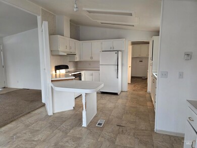 Kitchen featuring lofted ceiling, white appliances, light countertops, white cabinetry, and a peninsula
