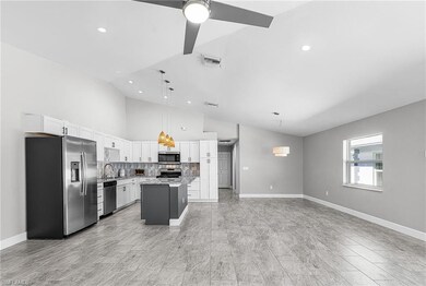 Kitchen featuring stainless steel appliances, a kitchen island, decorative backsplash, decorative light fixtures, and vaulted ceiling