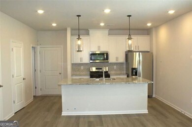 Kitchen featuring decorative backsplash, stainless steel appliances, a kitchen island with sink, recessed lighting, and white cabinets