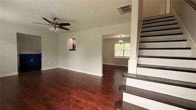 Unfurnished living room with stairs, a textured ceiling, wood finished floors, a ceiling fan, and baseboards