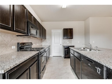 Kitchen featuring black appliances, dark brown cabinetry, light tile patterned floors, decorative backsplash, and light stone counters