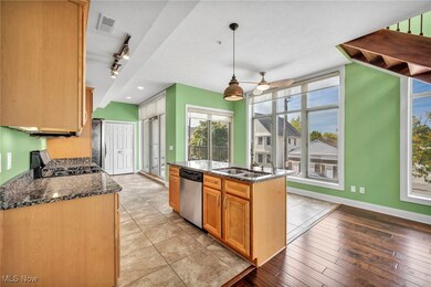 Kitchen featuring appliances with stainless steel finishes, an island with sink, light wood-type flooring, ceiling fan, and decorative light fixtures