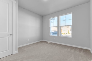 Empty room featuring light carpet and baseboards