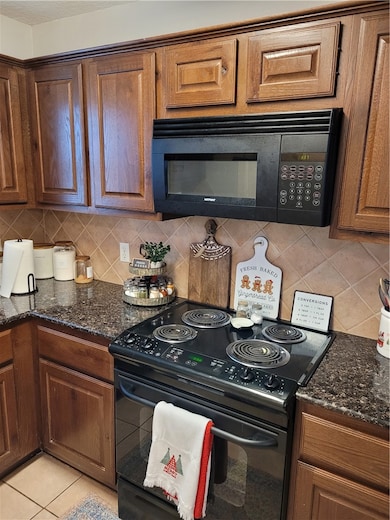 Kitchen with dark stone counters, light tile patte