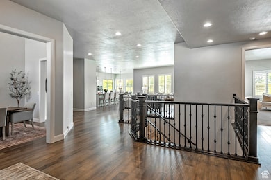Corridor featuring an upstairs landing, dark wood finished floors, recessed lighting, healthy amount of natural light, and a textured ceiling