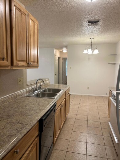 Kitchen featuring hanging light fixtures, dishwashing machine, stove, light tile patterned floors, and a textured ceiling