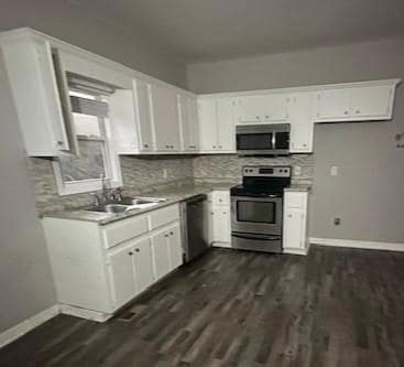 Kitchen featuring stainless steel appliances, white cabinetry, light countertops, and decorative backsplash