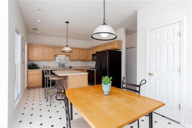 Kitchen featuring black appliances, light countertops, light brown cabinets, a kitchen island, and pendant lighting