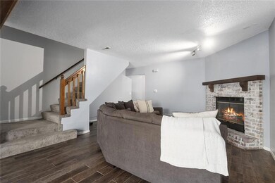 Living room featuring a brick fireplace, dark wood-type flooring, and a textured ceiling