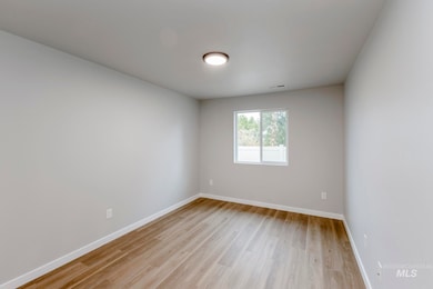 Spare room featuring baseboards and light wood-type flooring