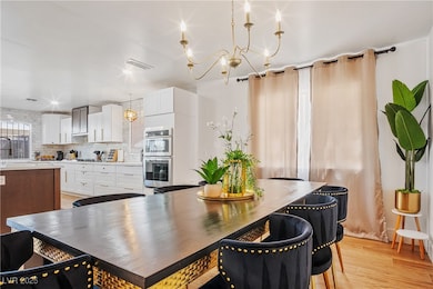 Dining room with light wood-style flooring and a chandelier