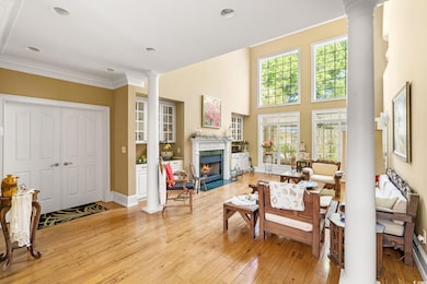 Living area with ornate columns, light wood-style floors, a premium fireplace, ornamental molding, and baseboards