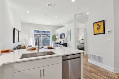 Kitchen featuring open floor plan, stainless steel dishwasher, white cabinets, recessed lighting, and light wood finished floors