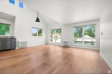 Unfurnished living room featuring heating unit, light wood-type flooring, and high vaulted ceiling