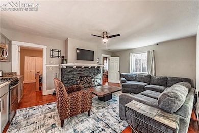 Living room featuring a ceiling fan, a fireplace, 