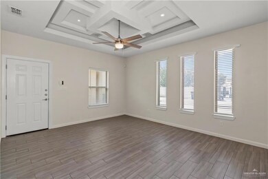 Spare room featuring light hardwood / wood-style flooring, coffered ceiling, ceiling fan, and a tray ceiling