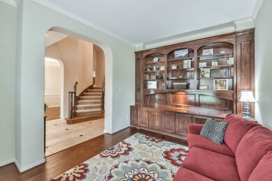 Formal Living Room, or Study features a wall of built in cabinets and shelving, engineered wood flooring, crown molding and neutral paint tones