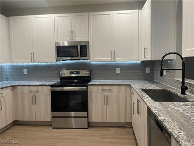 Kitchen featuring appliances with stainless steel finishes, light stone counters, tasteful backsplash, and light wood finished floors