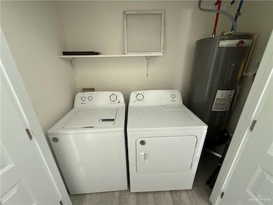 Laundry room featuring water heater, washing machine and clothes dryer, and light wood-type flooring