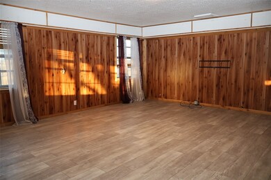 Empty room featuring a textured ceiling, light wood-style flooring, and wood walls