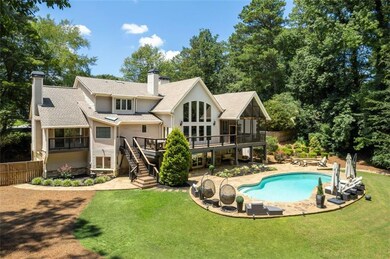 Rear view of house with a chimney, a sunroom, stairs, an outdoor pool, and a wooden deck