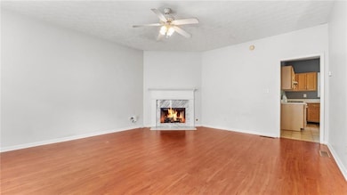 Unfurnished living room featuring light wood finished floors, a fireplace, and ceiling fan