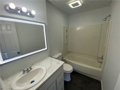 Bathroom with shower / tub combination, vanity, and dark tile patterned floors